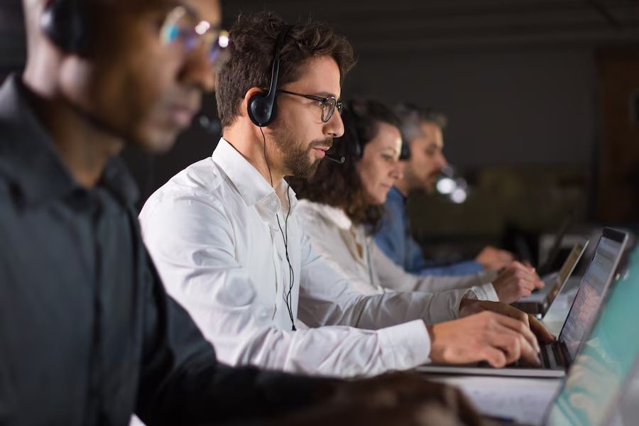 Contact center workers having a meeting in the office, with computers in front of them.