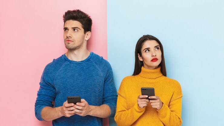 Young people looking confused while holding smartphones, representing the outdated Instagram hashtag strategy.