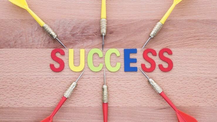 A wooden board with colorful darts targeting the word "success," symbolizing focus and strategy in marketing trends for 2025.