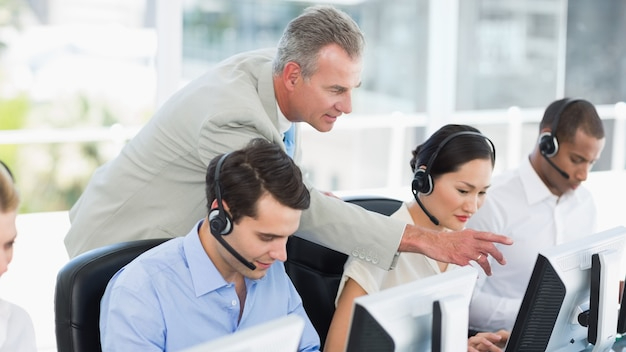 Manager guiding customer service representatives during a training session at a contact center to enhance customer experience