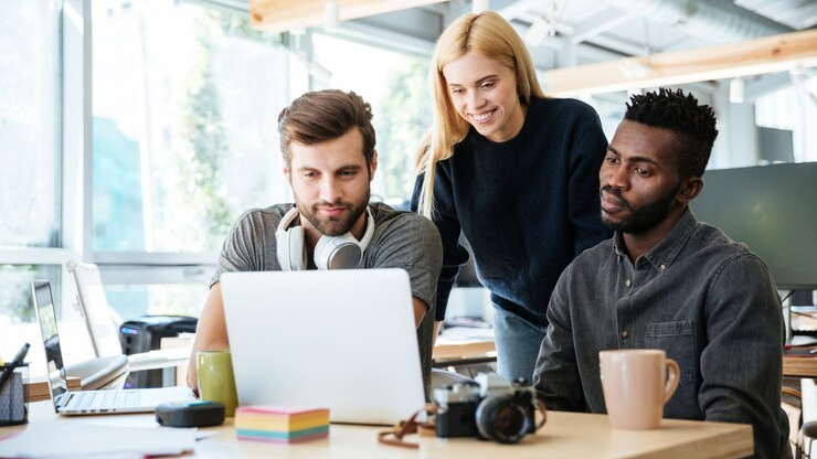 A group of marketing professionals collaborating on a laptop, discussing AI-driven digital marketing strategies using DeepSeek AI.